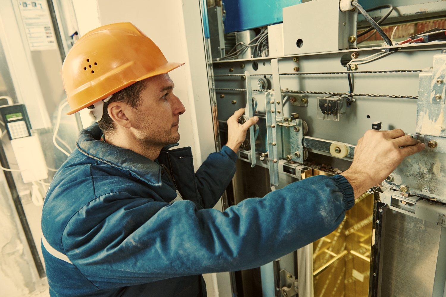 A technician in a hard hat working by hand on equipment in the field.